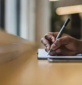 Person Writing in Note Pad with Pen