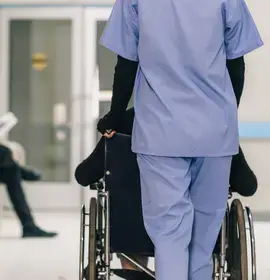 Nurse Pushing Wheelchair with Patient in Hospital