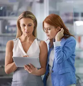 Two co-workers looking at a digital tablet in an office.