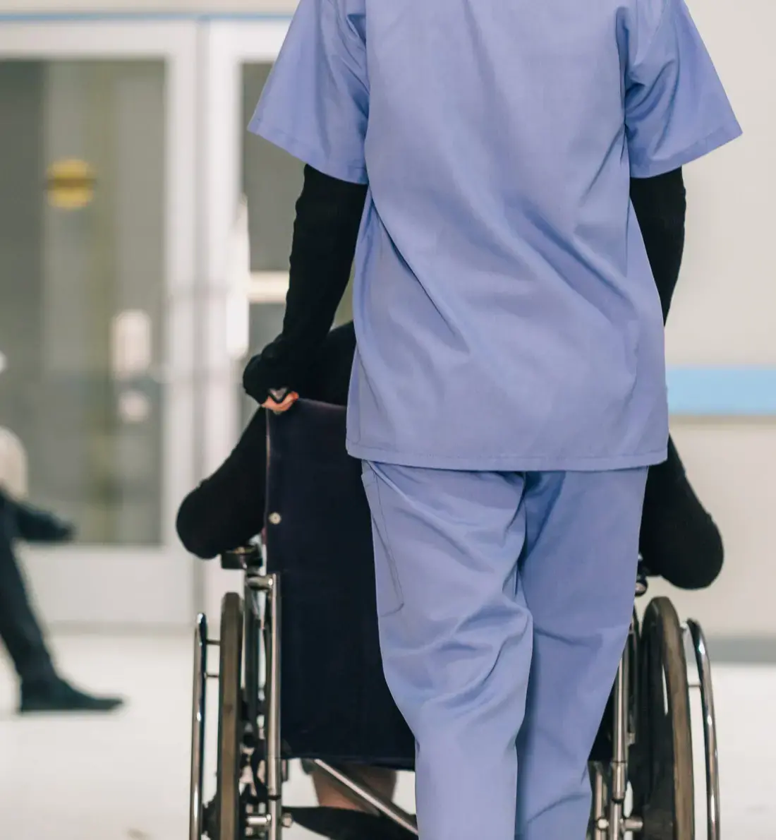 Nurse Pushing Wheelchair with Patient in Hospital