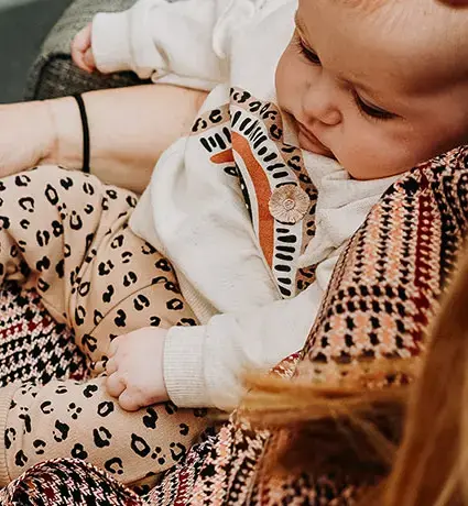 A baby is sitting on a woman's lap and they are browsing a law brochure.