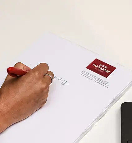 A woman is filling in a Smith Partnership form at a white desk.