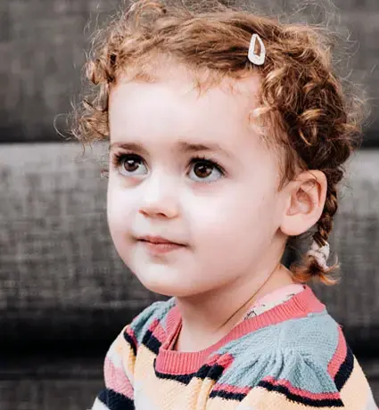 A young child is sitting on the floor in a colourfully striped top.