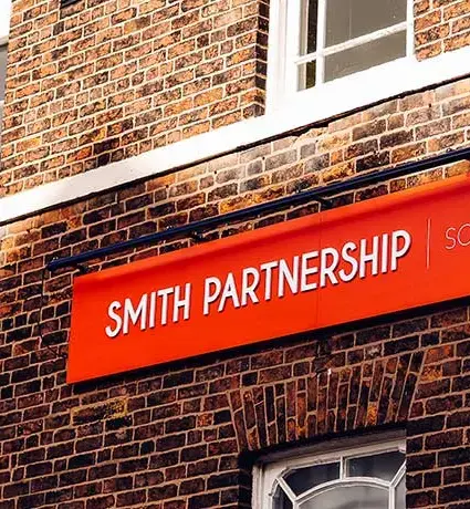 The outside of a brick building, with a red sign and white text reading Smith Partnership.